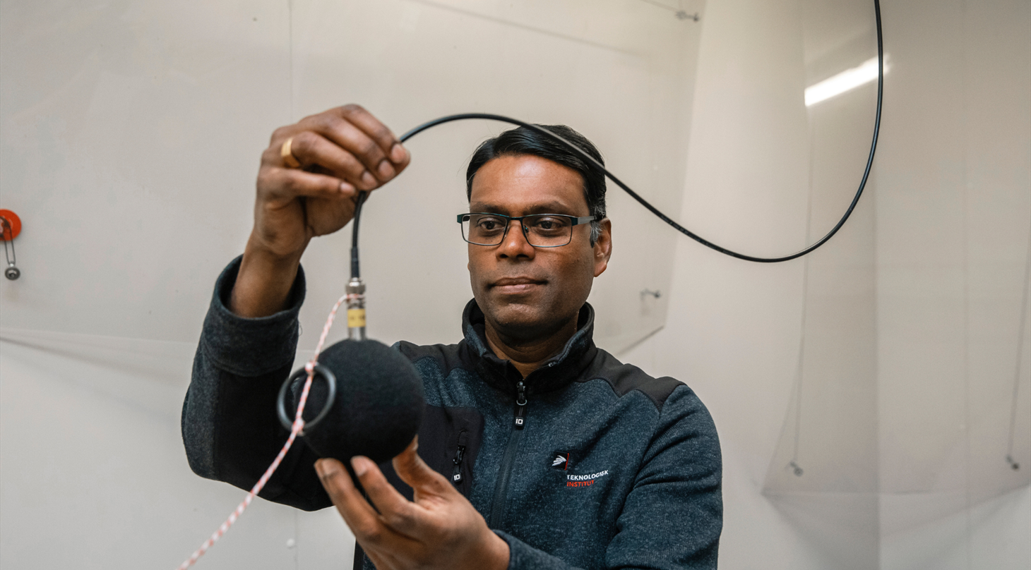 Billedet viser 1 person, der holder en mikrofon i Heat Pump Test Laboratory p� Teknologisk Institut